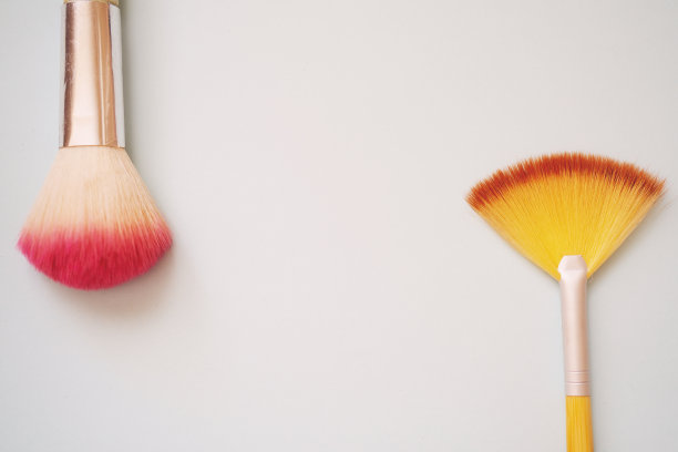 旧的腮红刷与腮红上化妆，选择性聚焦蓝色背景与文本空间。图片下载