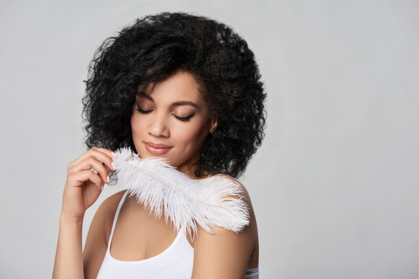 美丽的混血儿女人拿着白色的鸵鸟羽毛图片下载