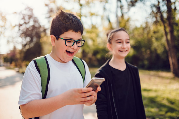 男孩和女朋友一起上学，用着智能手机图片下载