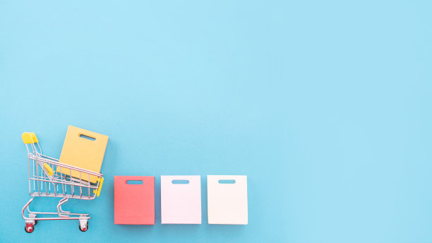 抽象的设计元素，年度销售，购物季节的概念，小黄色购物车与彩色纸袋在淡蓝色背景，俯视图，平铺图片下载