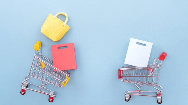 抽象的设计元素，年度销售，购物季节的概念，小黄色购物车与彩色纸袋在淡蓝色背景，俯视图，平铺图片下载