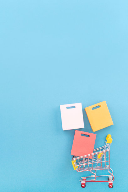 抽象的设计元素，年度销售，购物季节的概念，小黄色购物车与彩色纸袋在淡蓝色背景，俯视图，平铺图片下载