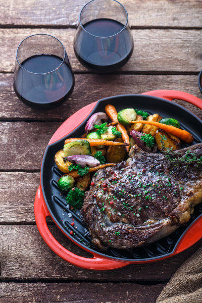 烤牛排在烤铁锅上，木制背景图片下载