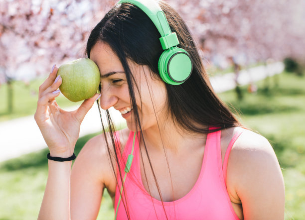 年轻女性穿着运动服和绿色苹果图片下载