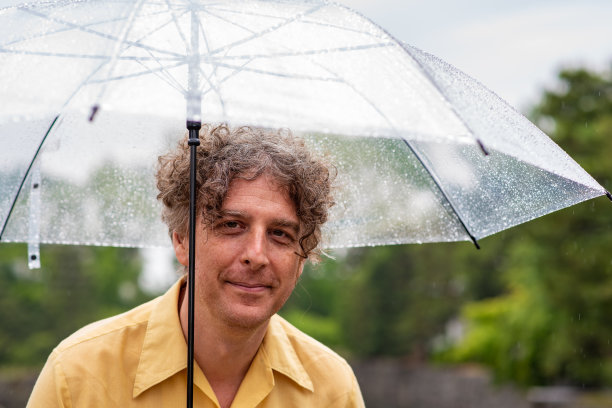 一个人带着伞，在雨天的户外。图片下载