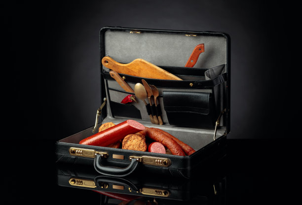 黑色皮箱，内装香肠、肉排和刀叉。概念形象上的主题是食物。图片下载