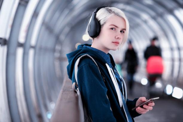 年轻的学生在地铁隧道里戴着大耳机听音乐图片下载