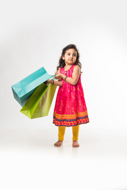 印度小女孩拿着购物袋，孤立地站在白色的背景上图片下载