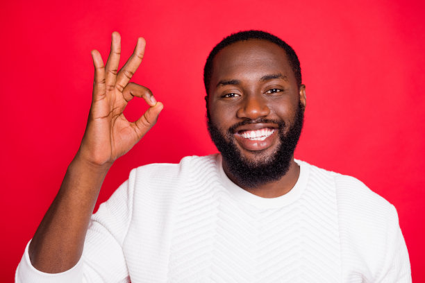 正面情绪的特写照片，凉爽的深色皮肤，男人显示ok标志，推荐促销广告，选择，决定促销，穿潮流装，孤立的红色背景图片下载