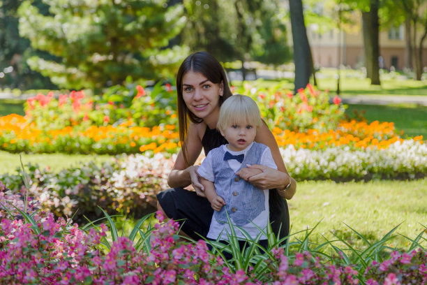 年轻的母亲和她的小儿子在花坛里图片下载