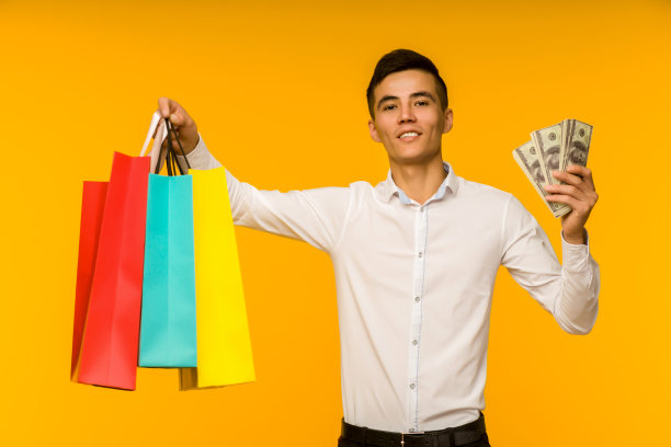 年轻的亚洲人展示他的购物袋和钱图片下载