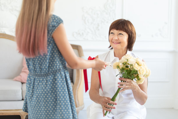 小女孩在母亲节给她的祖母一个带着红丝带的礼盒。有选择性的重点图片下载