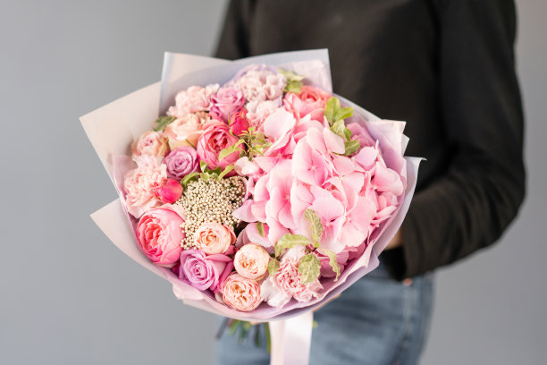 粉红色的颜色。女人手里捧着一束美丽的混合鲜花。花店花匠的工作。新鲜切花。图片下载