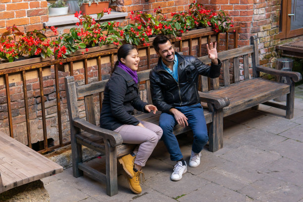 坐在户外长椅上的青年男女向别人打招呼图片下载