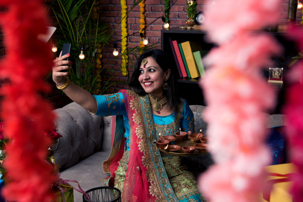 印度女孩拿着传统服饰的排灯节，点击自拍图片或通过智能手机说话。图片下载