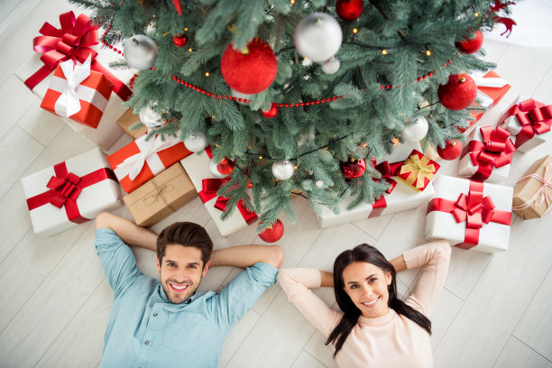 上面的高角度照片，两个迷人的浪漫的人与深色头发躺在地板上享受圣诞节圣诞节假期在房子里与礼物盒室内图片下载