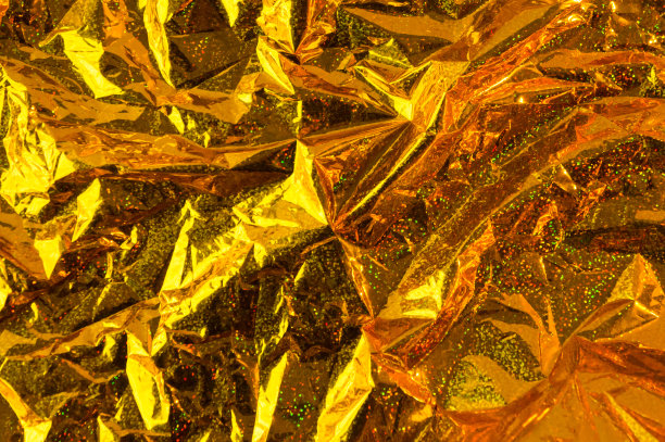 创意照片背景的金色全息褶皱箔与橙色的高光和阴影图片下载