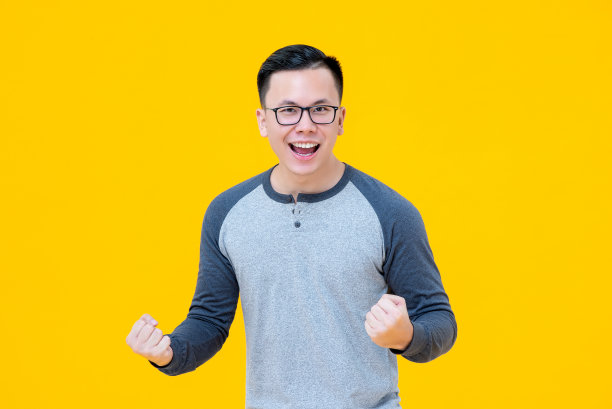 激动的获胜者亚洲人举起他的拳头与微笑的脸图片下载