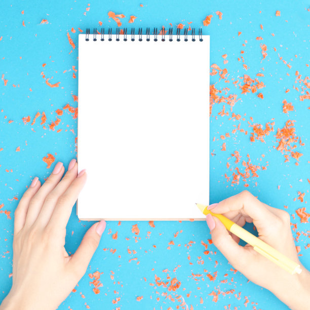 笔记本与女性的手在绿松石背景是孤立的。图片下载