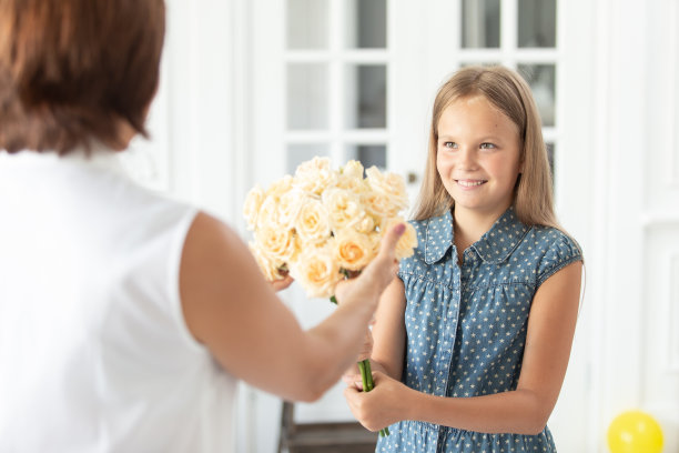 微笑的老妇人从穿着衣服的小女孩手中接过一束花。有选择性的重点图片下载