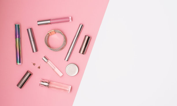 平铺组成装饰化妆品，香水和珠宝在粉红色和孤立的白色背景。化妆和美丽的概念。图片下载