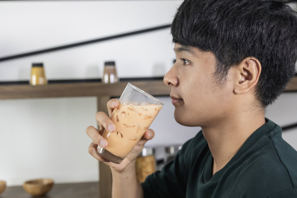 这位英俊的年轻人很高兴地喝着奶茶图片下载