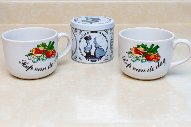 一对荷兰马克杯和一个蓝色的“糖浆华夫饼”罐头，这是一种荷兰茶或咖啡点心，在白色的背景上单独放置。图片下载