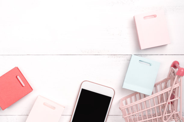 摘要网上购物，移动支付概念设计元素，彩色购物车和纸袋在白色木制桌子的背景。图片下载