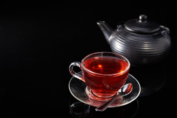 黑色背景上的热红茶和茶壶玻璃杯。图片下载