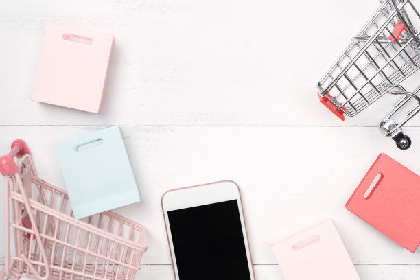 摘要网上购物，移动支付概念设计元素，彩色购物车和纸袋在白色木制桌子的背景。图片下载