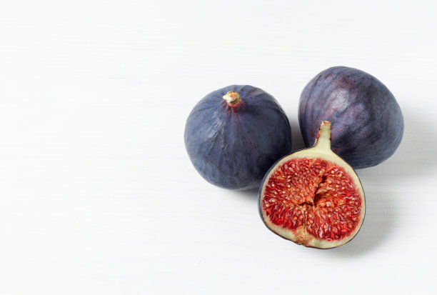 新鲜成熟的无花果白色背景与文字空间。食物的照片。副本的空间。有红色种子的紫色无花果。侧视图。食品的概念图片下载