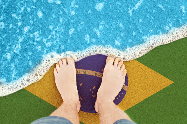 脚在阳光明媚的沙滩与国旗巴西。从上往下看图片下载