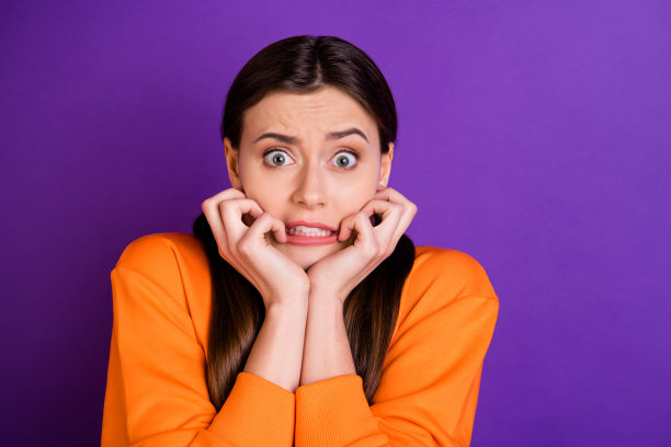 近距离的照片沮丧害怕的年轻女孩马尾辫听到可怕的消息咬指甲穿青少年运动服兜帽孤立的紫色紫色的背景图片下载