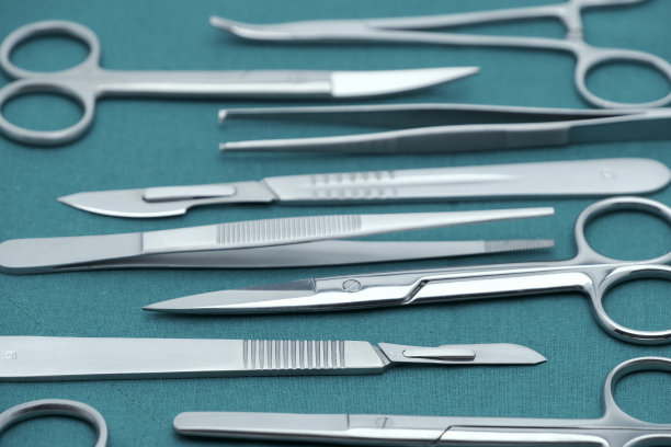 基本的外科器械手术刀、镊子、镊子、剪刀在外科的绿色褶皱织物上图片下载