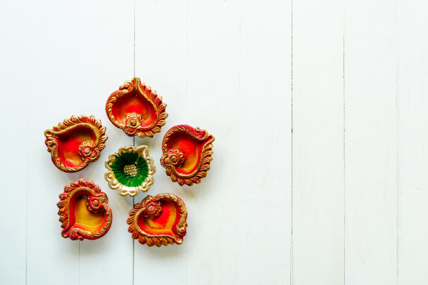 快乐的排灯节-粘土Diya灯点燃在排灯节，印度节日的灯庆祝。白色木质背景上的彩色传统油灯图片下载