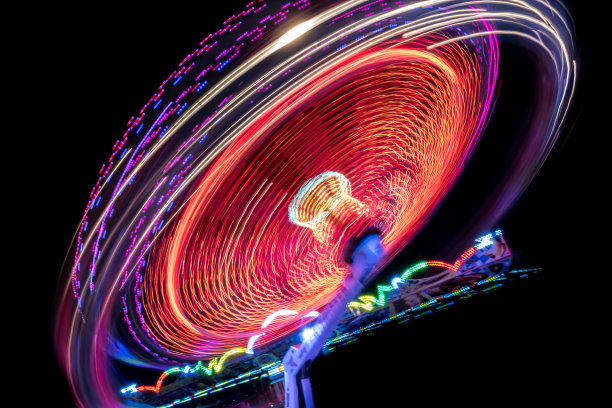 在一个有趣的公园里，从快速旋转木马上走出来的彩色灯光图片下载