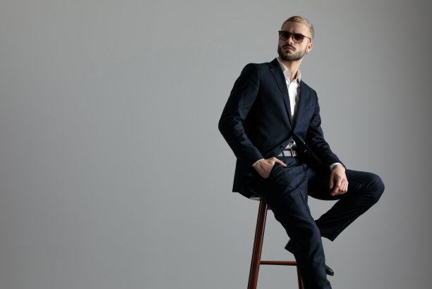 商人坐在一条腿休息的椅子上，看着一边沉思图片下载