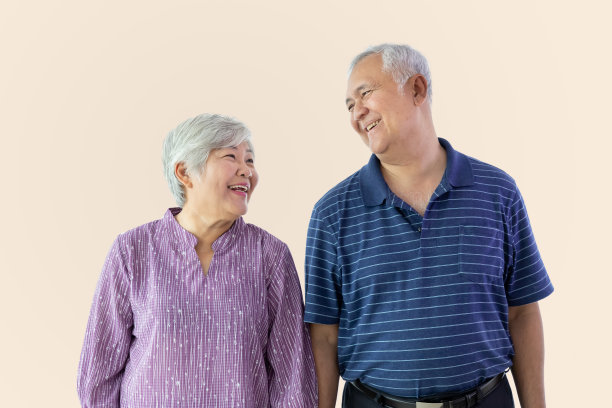 快乐的老夫老妻夫妇孤立地在米色背景上微笑，互相看着对方图片下载