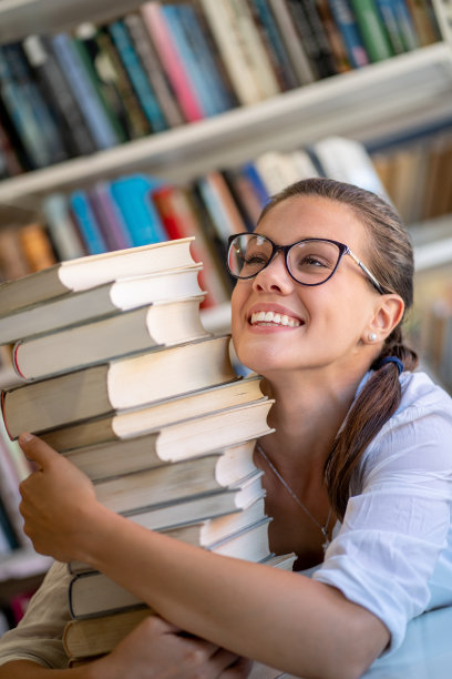 微笑的年轻女人拥抱一堆书图片下载
