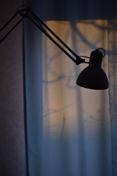 一盏台灯的剪影在一扇窗户的背景上，在早上的黎明，工作到早上，晚上工作。图片下载