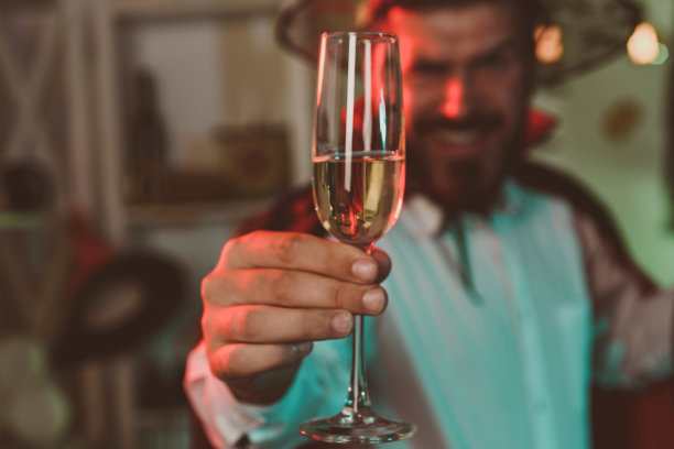一杯白葡萄酒。万圣节派对。有趣的人。酒精。胡须男享受派对。10月的心情。性感的帅哥。图片下载