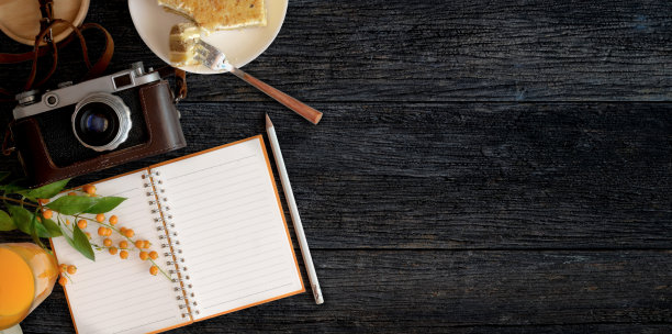 舒适的工作空间，一个空白的笔记本，烤面包和一杯橙汁的黑色木桌背景图片下载