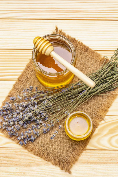 新鲜液体蜂蜜在玻璃罐中与一个木制的蜂蜜勺。健康糖营养概念图片下载