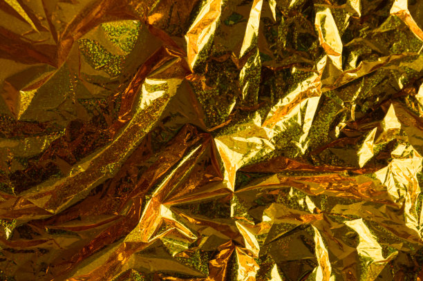 创意照片背景的金色全息褶皱箔与橙色的高光和阴影图片下载