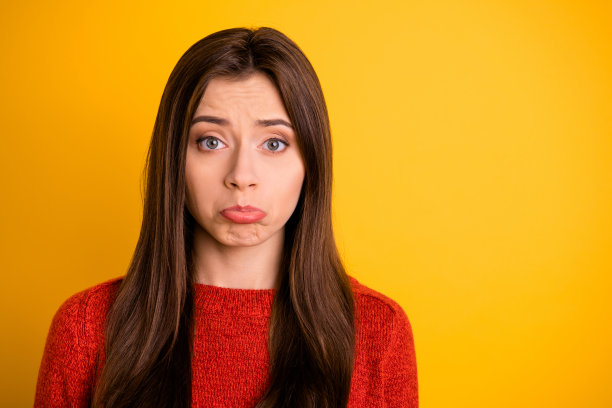近距离的照片失望，难过的女孩与她的男友有分歧，感到内疚，抱歉，哭泣穿红色套衫孤立在黄色背景图片下载