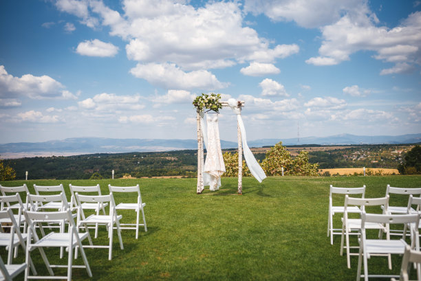 白色的婚纱挂在户外的婚礼拱门上。美丽的夏日风景背景图片下载