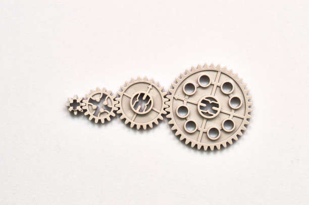 不同尺寸的玩具齿轮代表团队的工作相互连接在纸背景上图片下载