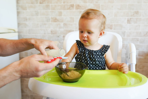 宝宝和爸爸在厨房里，小女孩在椅子上吃东西图片下载