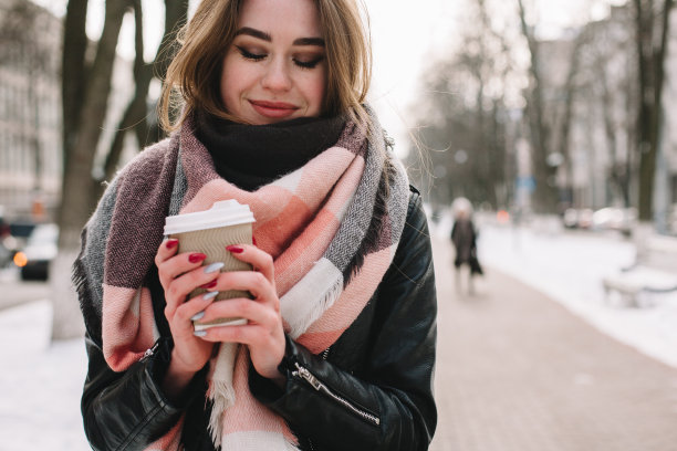 冬天，带着一次性杯子走在街上的幸福女人图片下载