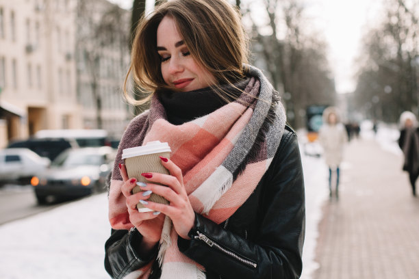 冬天，带着一次性杯子走在街上的幸福女人图片下载